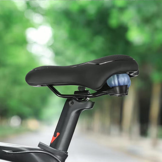 Fahrradsattel Deluxe Komfort, montiert auf einem Fahrrad, im Hintergrund eine grüne Allee. Zeigt den Sattel im Einsatz in natürlicher Umgebung.