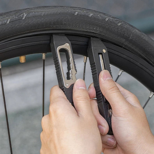 Alt-Text: Hände nutzen 16-in-1 Fahrrad Multitool Reifenheber, um einen Fahrradreifen schnell und einfach zu demontieren