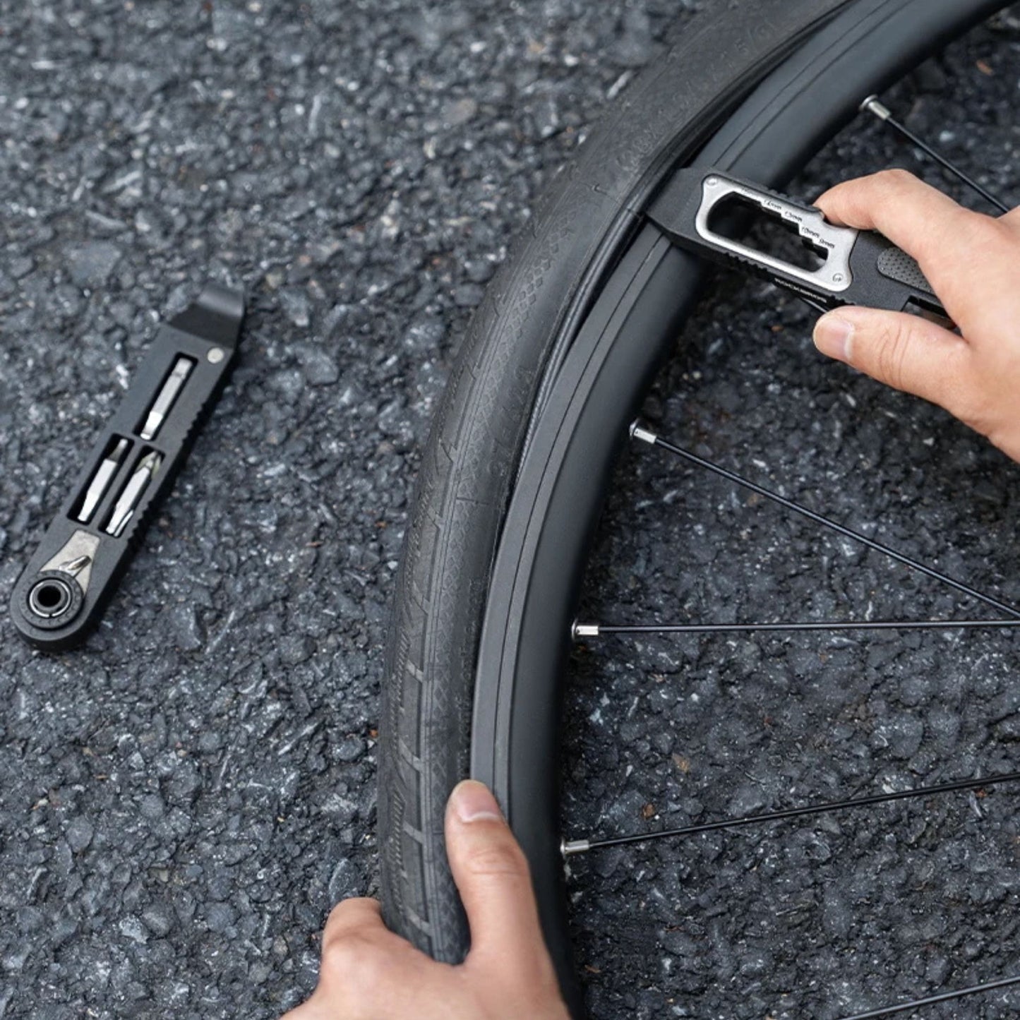 Hand entfernt Fahrradreifen mit 16-in-1 Multitool Reifenheber auf der Straße, ideal für schnelle Notfallreparaturen unterwegs