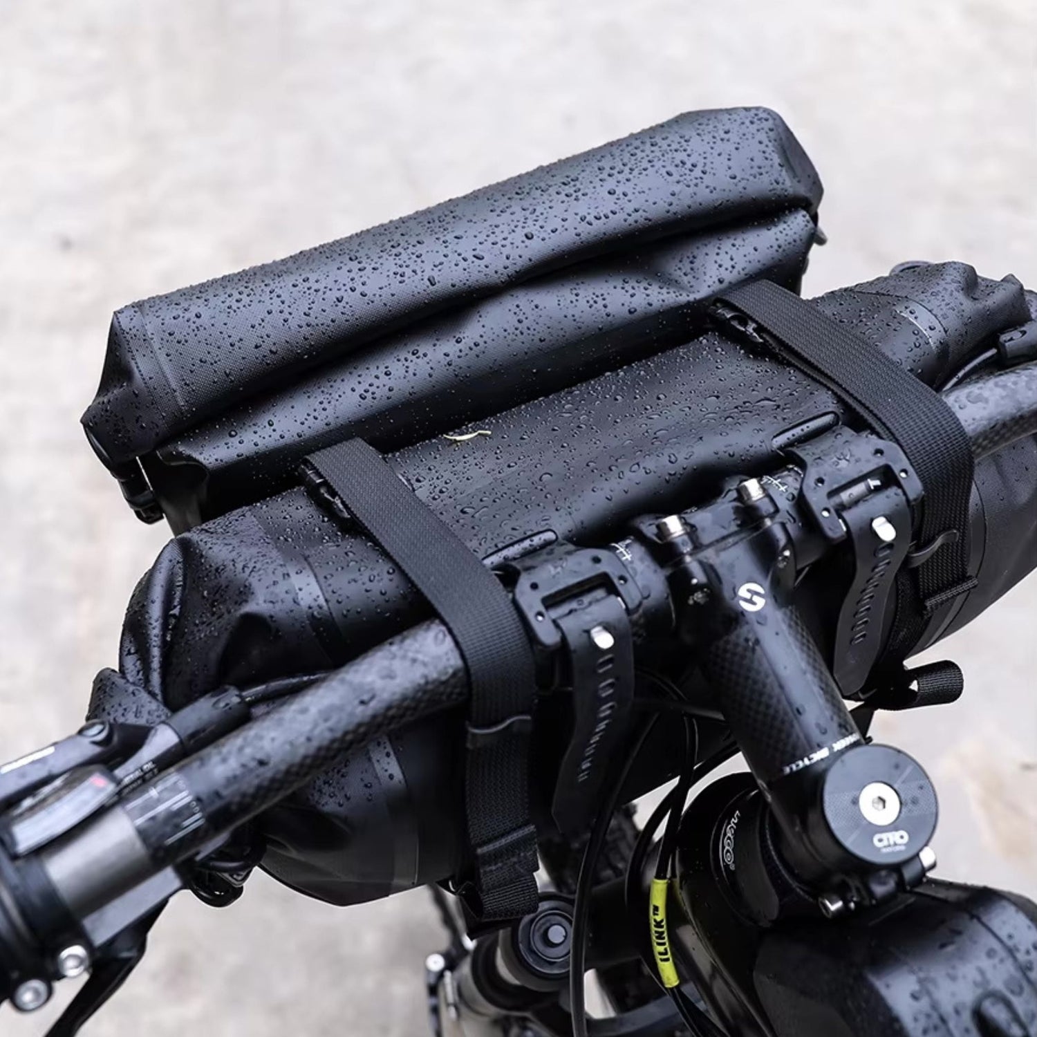 Rhinowalk Fahrrad-Lenkertaschen, schwarzes, wasserdichtes Design, nass, befestigt am Fahrradlenker, Nahaufnahme mit Details zu Schnallen und Material.