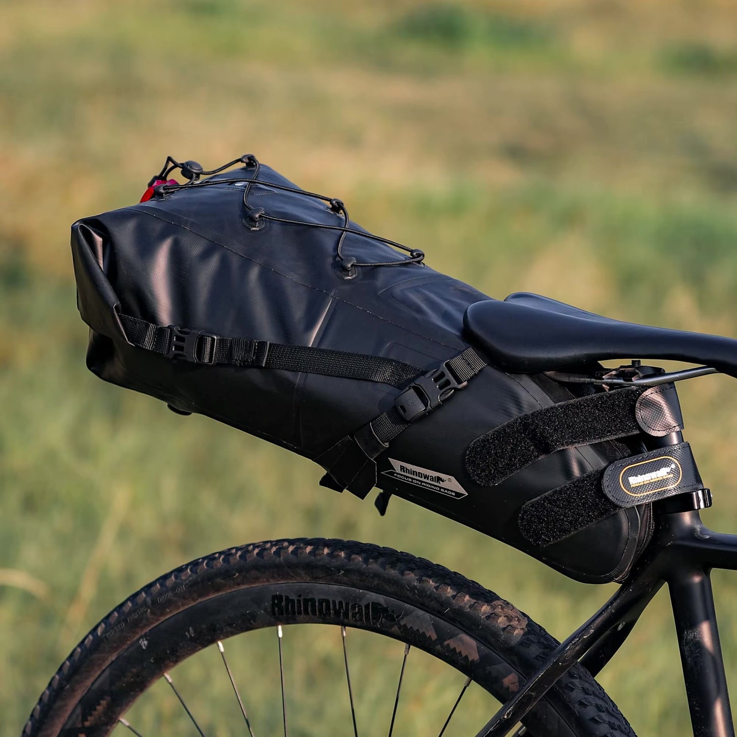 Rhinowalk Bikepacking Satteltasche im Einsatz: Ein Fahrrad mit der Tasche steht auf einer Wiese. Bereit für das nächste Abenteuer.