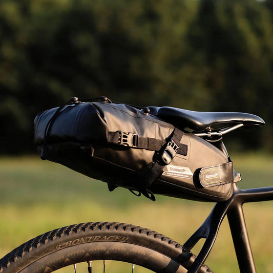 Rhinowalk Bikepacking Satteltasche (10L) im Einsatz bei einer Radtour im Sonnenuntergang. Die Tasche fügt sich harmonisch ins Bild ein.