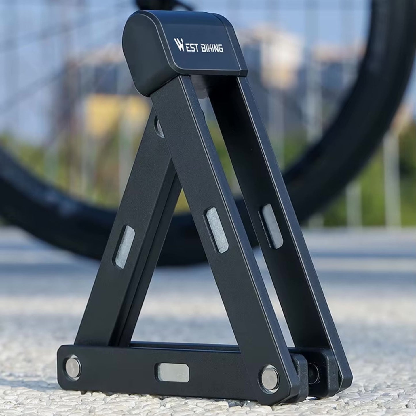 Hochsicherheits-Faltschloss im aufgeklappten Zustand vor einem Fahrrad. Bereit für den Einsatz.
