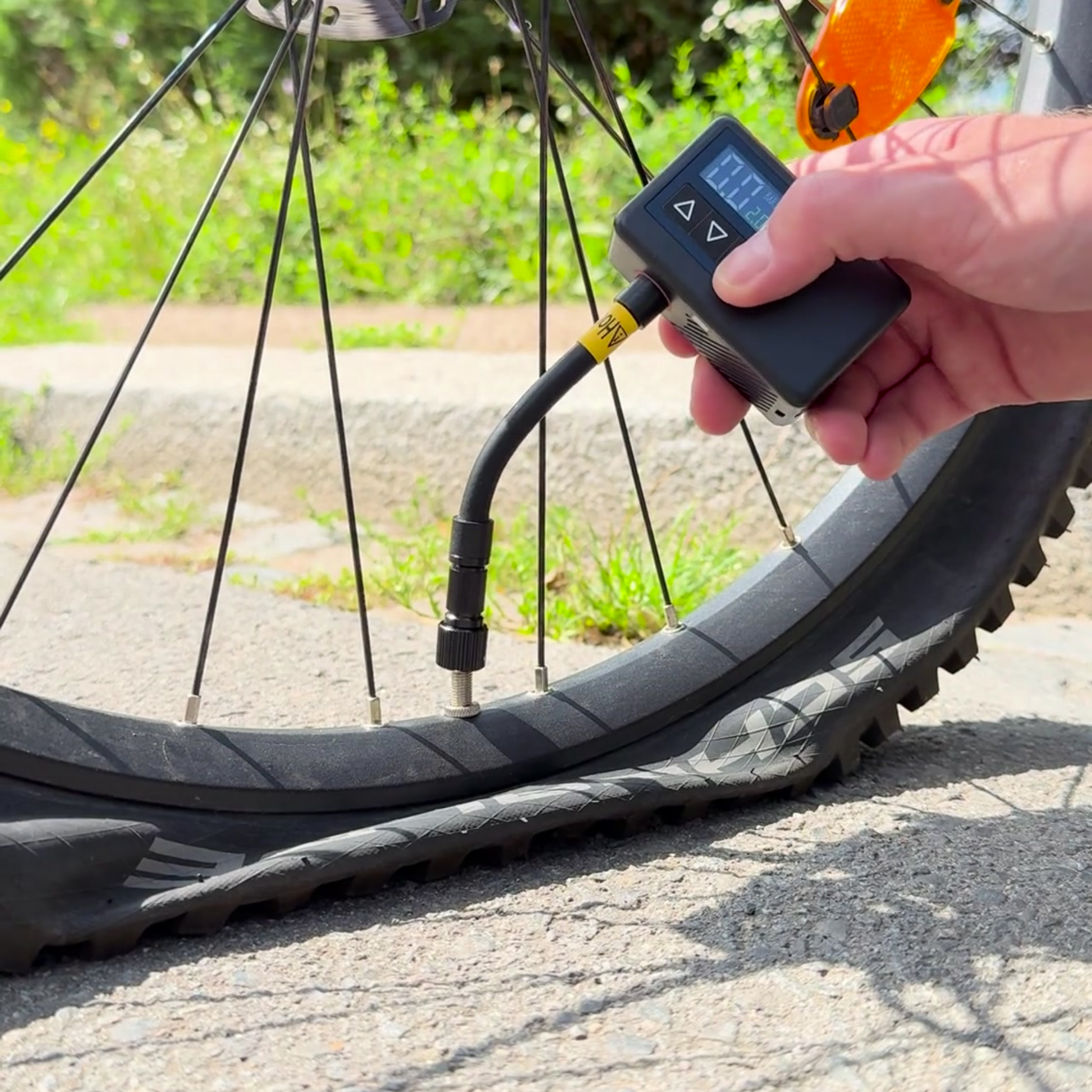 offtrails e-Pump, aufpumpen ohne Hände, Produktvideo Cover, Hand hält elektrische Fahrradpumpe ans Ventil